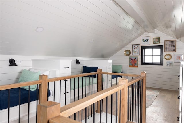 corridor with hardwood / wood-style flooring, lofted ceiling with beams, and wood walls