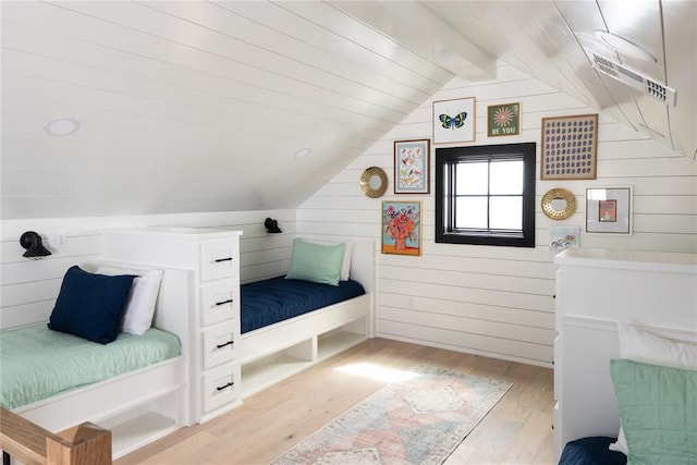 bedroom with light wood-type flooring, lofted ceiling with beams, and wooden walls