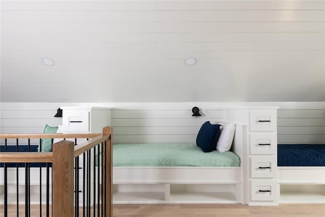 bedroom with light wood-type flooring and wood walls