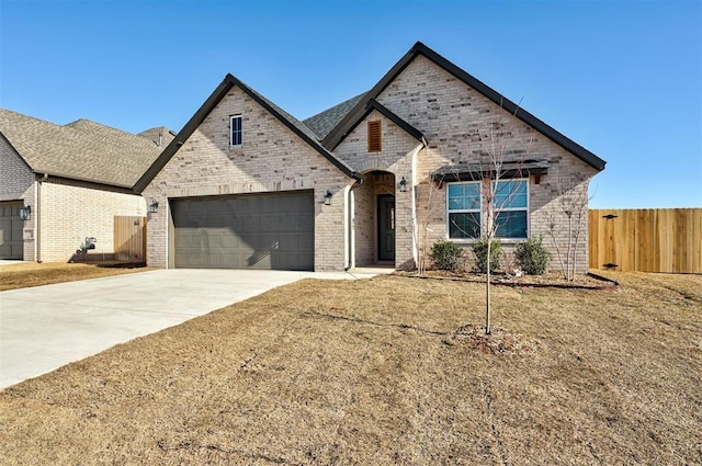 french country home featuring concrete driveway and brick siding