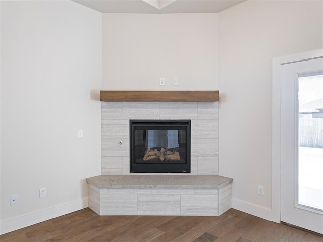 interior details featuring a tile fireplace and hardwood / wood-style floors