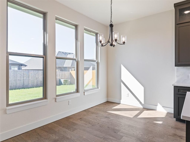 unfurnished dining area featuring a notable chandelier and light wood-type flooring