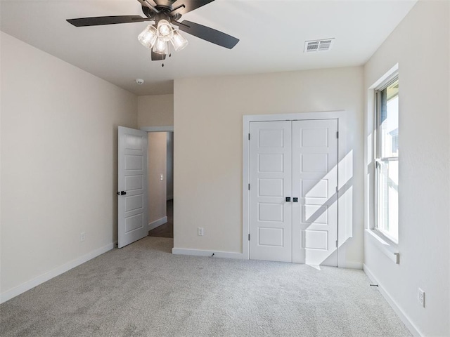 unfurnished bedroom with ceiling fan, light carpet, and a closet