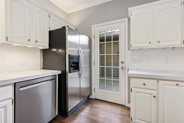 kitchen with dark hardwood / wood-style floors, decorative backsplash, ornamental molding, white cabinetry, and stainless steel appliances