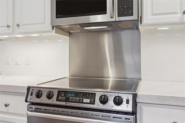 kitchen with decorative backsplash, white cabinetry, and appliances with stainless steel finishes