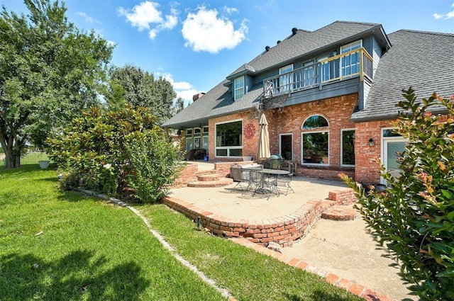 rear view of house with a yard, a patio, and a balcony