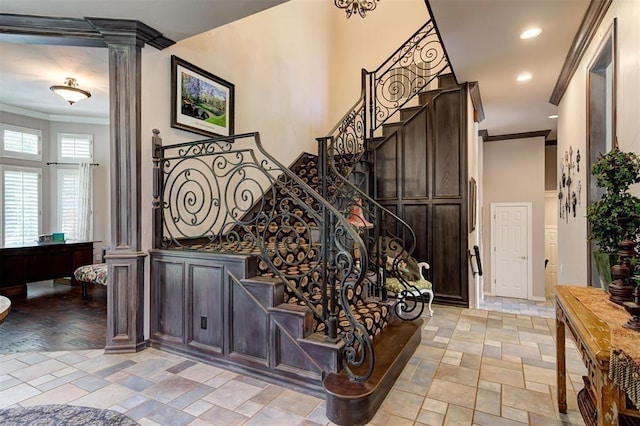 stairway with decorative columns, crown molding, and hardwood / wood-style flooring