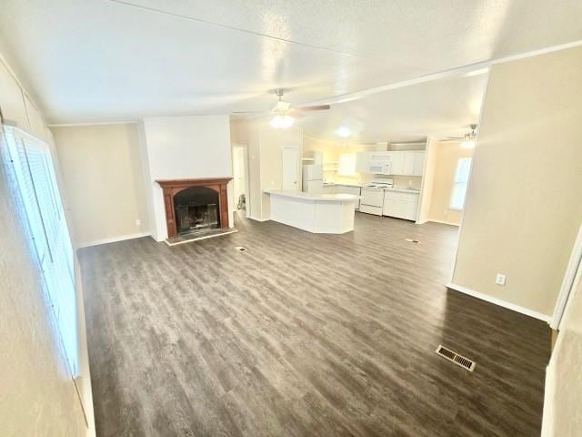 unfurnished living room with ceiling fan and dark wood-type flooring