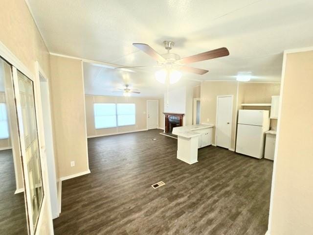 unfurnished living room with ceiling fan, crown molding, and dark wood-type flooring