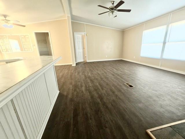 unfurnished living room with ornamental molding, dark hardwood / wood-style flooring, ceiling fan, and lofted ceiling