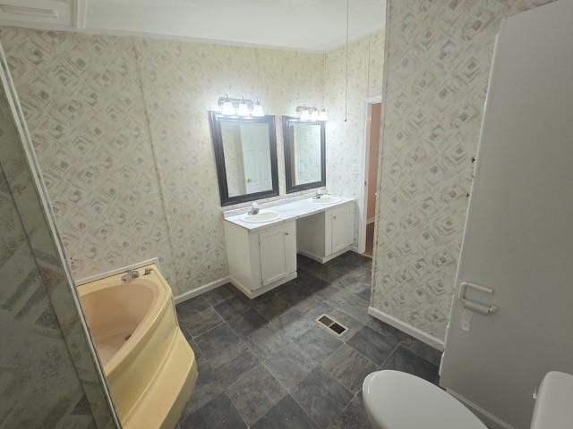 bathroom featuring vanity, toilet, and a tub to relax in