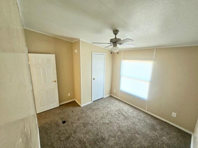 unfurnished bedroom featuring dark colored carpet, ceiling fan, and a textured ceiling