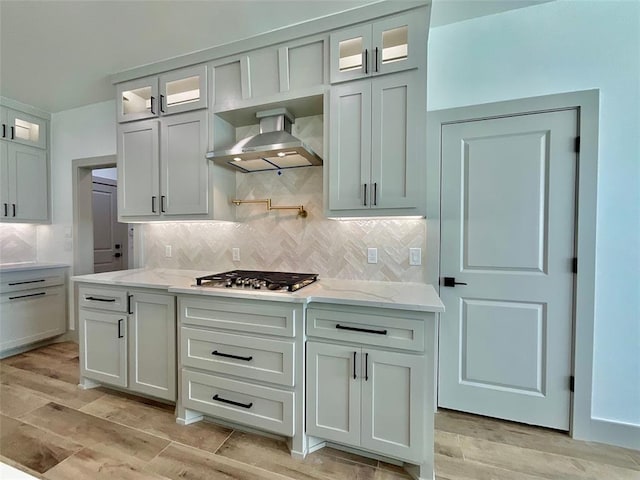 kitchen featuring light wood-type flooring, tasteful backsplash, and wall chimney exhaust hood