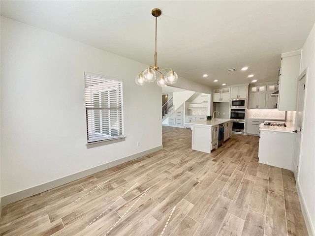 kitchen featuring a center island with sink, sink, light hardwood / wood-style flooring, white cabinetry, and stainless steel appliances