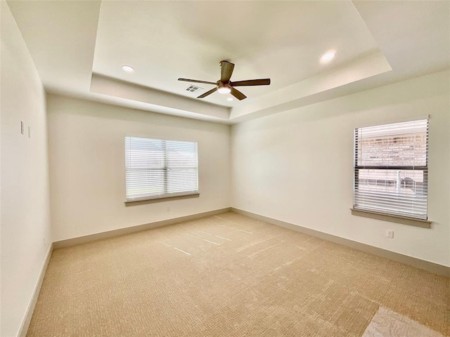 carpeted spare room featuring a raised ceiling and ceiling fan