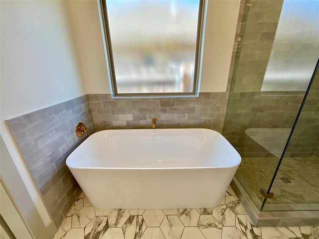 bathroom featuring a bath and tile walls