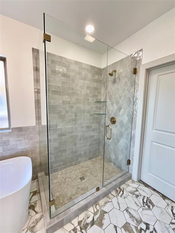 bathroom with tile walls and independent shower and bath