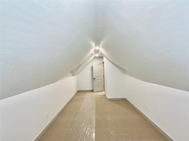 bonus room with light carpet and vaulted ceiling