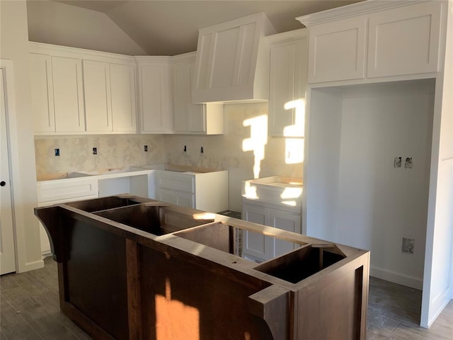 kitchen with tasteful backsplash, white cabinets, wood-type flooring, and vaulted ceiling