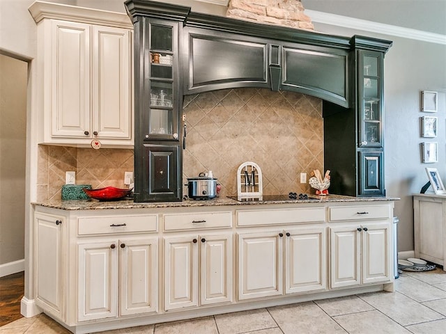 kitchen with decorative backsplash, crown molding, light tile patterned floors, and light stone countertops