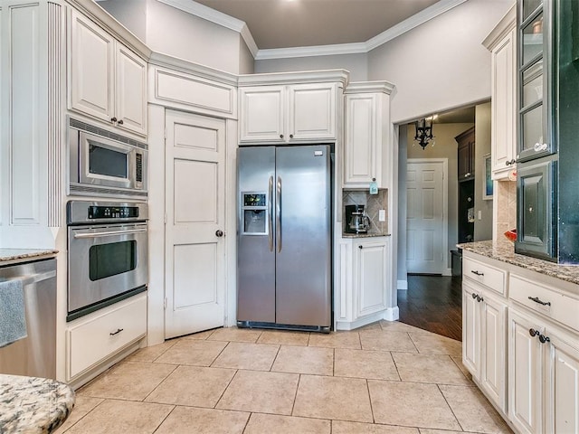 kitchen featuring white cabinets, crown molding, stainless steel appliances, and tasteful backsplash