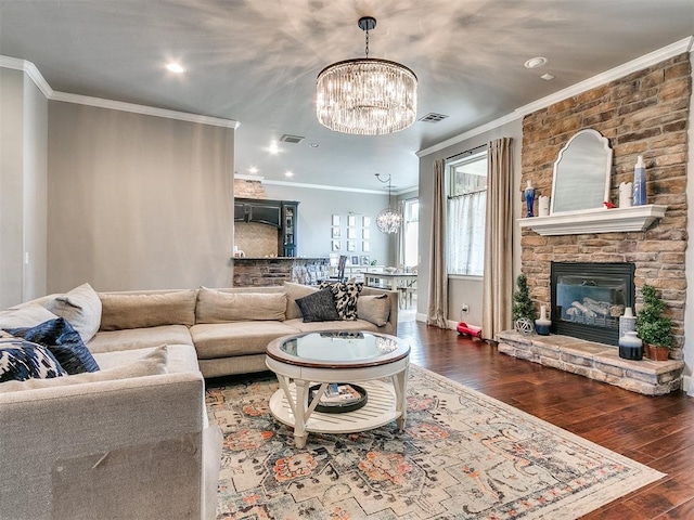 living room with a notable chandelier, dark hardwood / wood-style floors, ornamental molding, and a fireplace