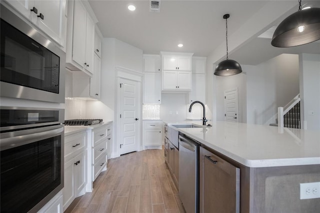 9317 Cheek Ranch Rd, Yukon, OK 73099 - kitchen featuring visible vents, appliances with stainless steel finishes, a sink, light wood-style floors, and an island with sink