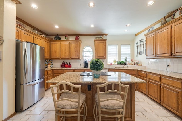 kitchen featuring a breakfast bar, a center island, stainless steel fridge, ornamental molding, and tasteful backsplash