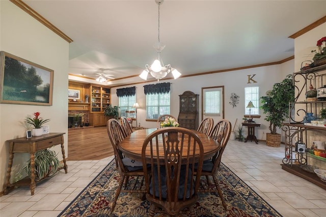 dining area with ceiling fan with notable chandelier, built in features, crown molding, and a wealth of natural light