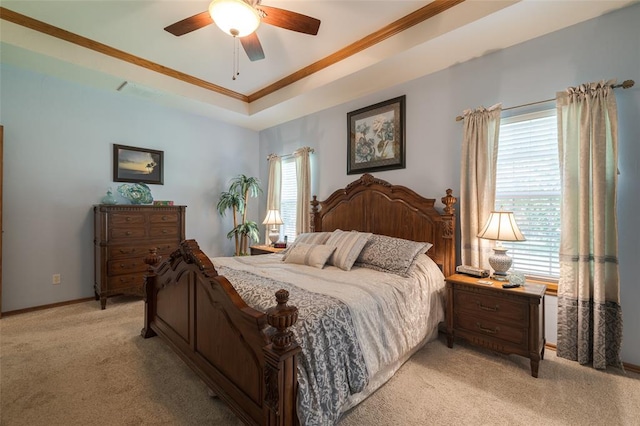 carpeted bedroom with a tray ceiling, multiple windows, ceiling fan, and ornamental molding