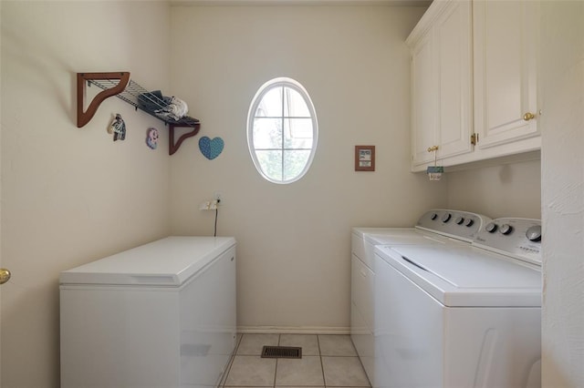 clothes washing area featuring cabinets, light tile patterned floors, and washer and dryer