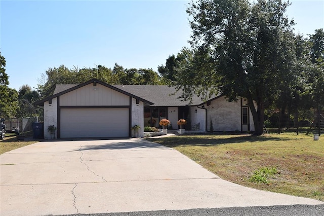 view of front of property featuring a front yard, brick siding, concrete driveway, and an attached garage