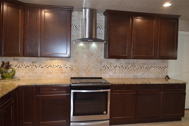 kitchen with backsplash, wall chimney range hood, electric range, light stone countertops, and dark brown cabinets