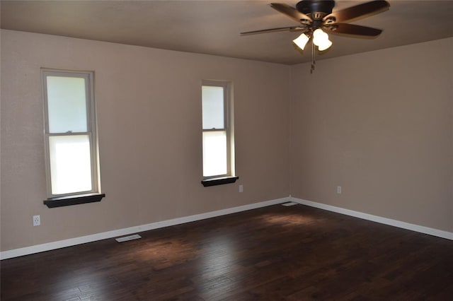 spare room with plenty of natural light, ceiling fan, and dark wood-type flooring