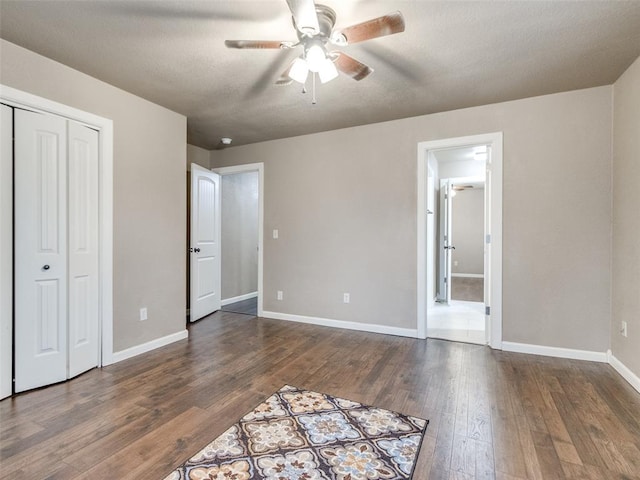 unfurnished bedroom with baseboards, dark wood finished floors, ceiling fan, a closet, and a textured ceiling