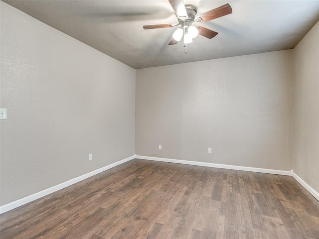 empty room featuring dark wood finished floors, a ceiling fan, and baseboards