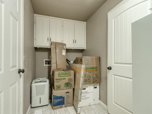 clothes washing area featuring cabinet space, hookup for a washing machine, and baseboards