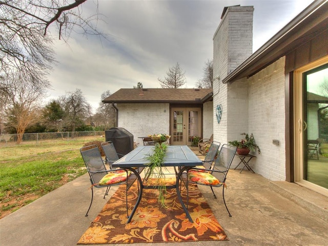 view of patio with french doors, outdoor dining area, and fence