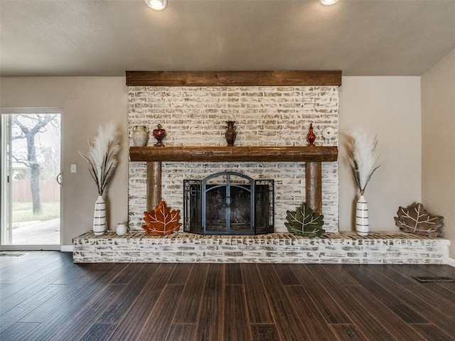 unfurnished living room featuring a textured ceiling, a brick fireplace, and wood finished floors