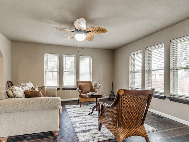 living area featuring plenty of natural light, dark wood-type flooring, and a ceiling fan