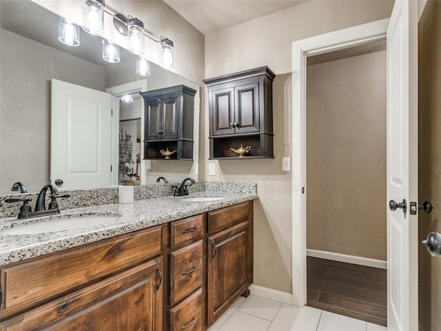 full bathroom featuring double vanity, baseboards, tile patterned floors, and a sink