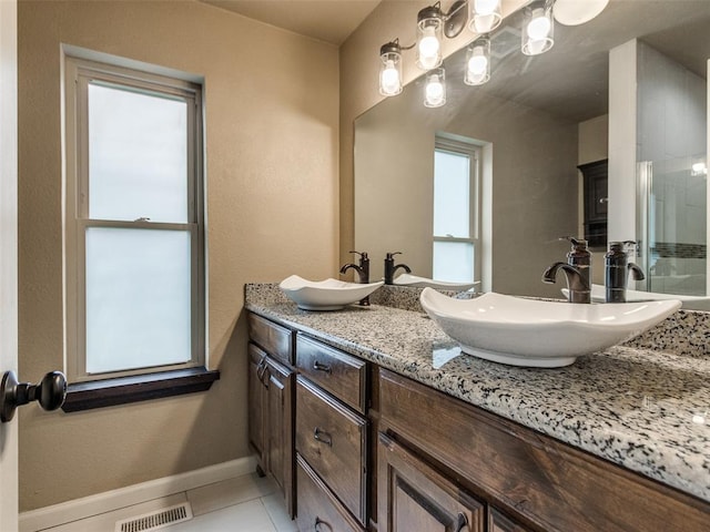 bathroom with a sink, visible vents, baseboards, and tile patterned flooring