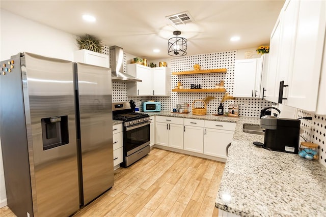 kitchen featuring light stone countertops, wall chimney exhaust hood, light hardwood / wood-style flooring, white cabinets, and appliances with stainless steel finishes