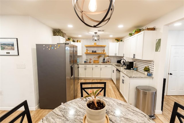 kitchen with white cabinets, decorative backsplash, stainless steel appliances, and light hardwood / wood-style floors