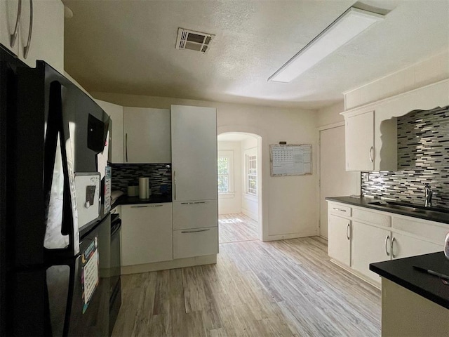 kitchen featuring black appliances, light hardwood / wood-style flooring, sink, and tasteful backsplash