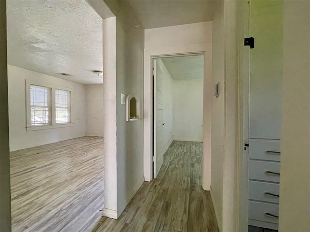 corridor featuring light hardwood / wood-style floors and a textured ceiling