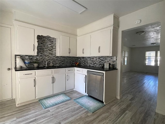 kitchen with decorative backsplash, stainless steel dishwasher, sink, white cabinets, and hardwood / wood-style floors