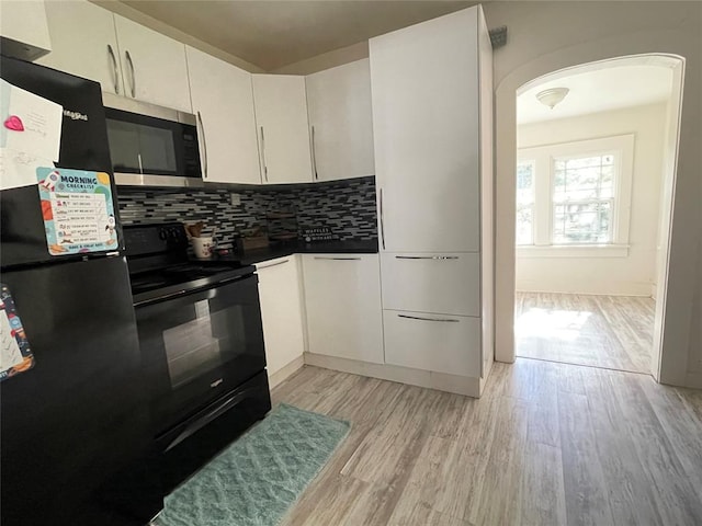 kitchen featuring white cabinets, decorative backsplash, light hardwood / wood-style floors, and black appliances