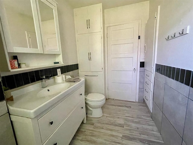 bathroom featuring decorative backsplash, vanity, wood-type flooring, and toilet