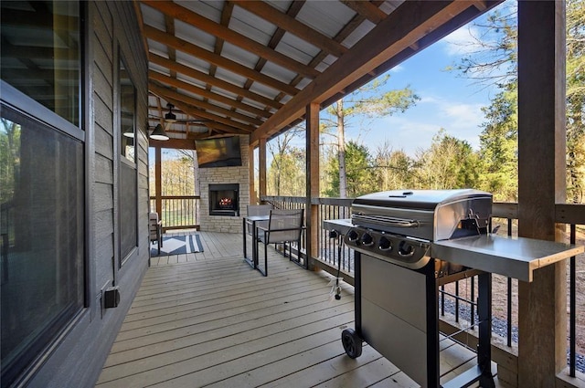 wooden deck with an outdoor stone fireplace and grilling area